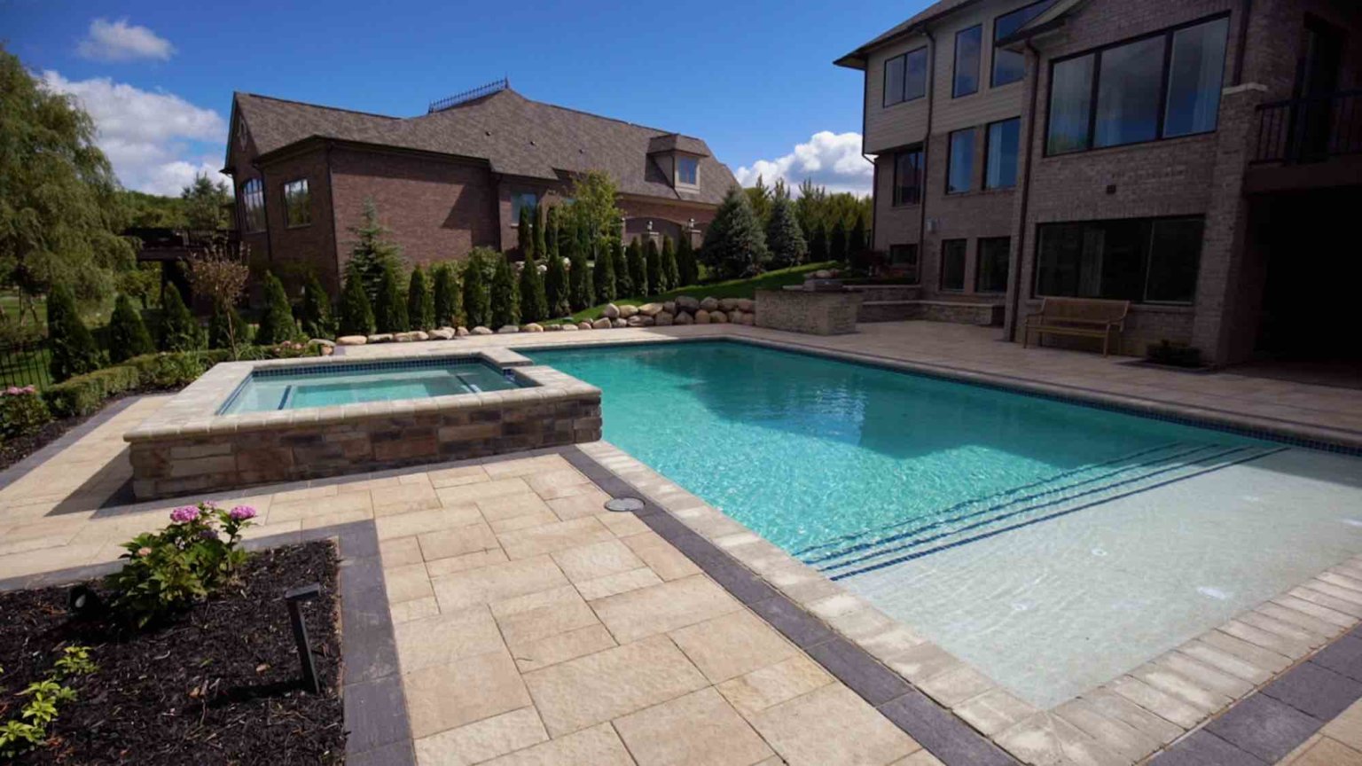 landscape design, michigan pool design, paving company in Michigan, inground pool, pool inspo, backyard pool, pavers, pavers near me, swim and spa, swimming pool design and install, backyard ideas, privacy fence ideas, backyard landscaping ideas, inground pool ideas, gunite pools, pool lights, led pool lights, unilock, Oakland County pavers, pavers near me, pool design, patio paving Oakland County, patio pavers near me, unilock contractors inground pool with raised spa spillover spa