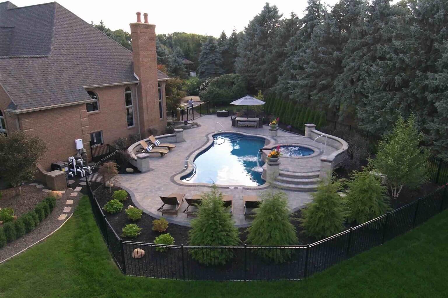 aerial view of backyard pool with hot tub spillover attached