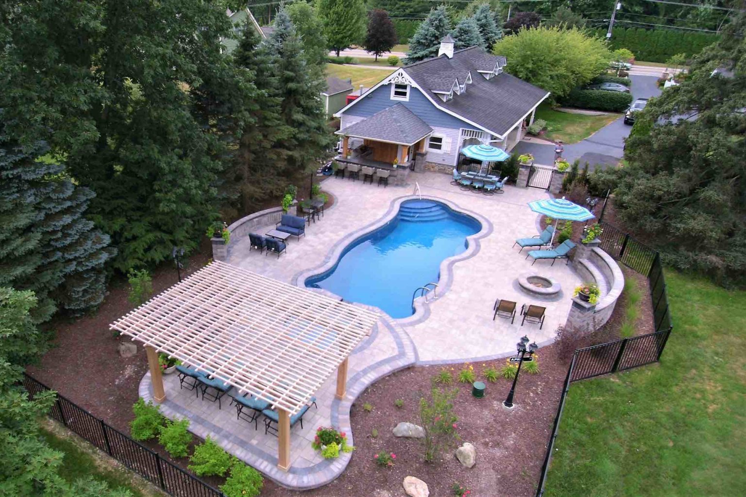 aerial view of pool and poolside lounge with outdoor kitchen and fire pit